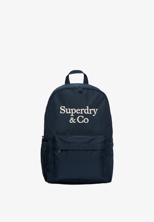 Marineblå rygsæk med frontlynlåslomme og "Superdry & Co" broderet i beige foran. Øverste håndtag og justerbare stropper er synlige.