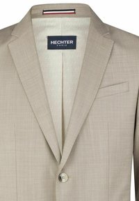 Beige Blazer aus glattem Stoff, mit Reverskragen, einreihiger Knopfverschluss und einem dezenten Muster im Futter. Das Etikett trägt die Aufschrift "HECHTER PARIS."