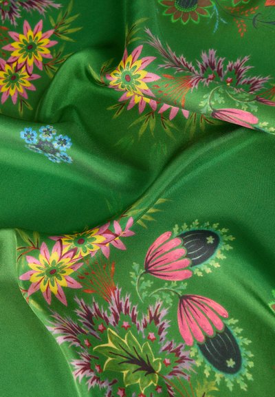 Πράσινο μεταξωτό ύφασμα με πολύχρωμα λουλουδένια σχέδια σε ροζ, κίτρινο, μωβ και μπλε, που δείχνει πτυχώσεις και λεπτομέρειες υφής.