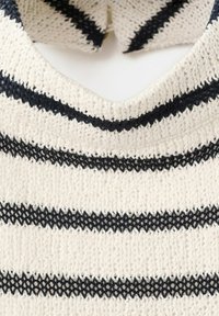 Pull tricoté crème avec des rayures horizontales noires et un col en V, montrant une texture détaillée et des motifs de couture.