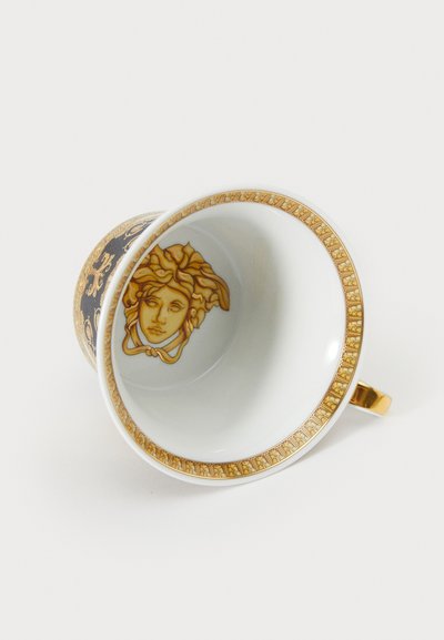 Keramikkop med gulddetaljer, sort yderside med udsmykkede mønstre og en Medusa-motiv indeni. Blank overflade, buet håndtag.