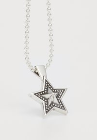 Sudraba zvaigznes formas piekariņš ar teksturētu virsmu, ar mazām apļveida akcentiem, pievienots pie krellēm veidota kaklarota.