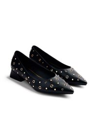 Zapatos de salón de piel negra con tacón bajo y punta afilada, adornados con tachuelas circulares doradas de diferentes tamaños en la superficie superior.