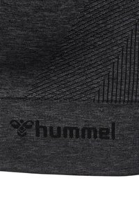 Tissu gris foncé avec des lignes texturées diagonales et le nom de la marque « hummel » avec son logo abeille brodé près du bord inférieur.