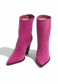 Roze zamšaste gležnjače s oštrim vrhom i crnim, suženim potplatom. Glatka tekstura i minimalistički dizajn bez vidljivih detalja.