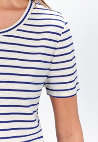 Gestreept t-shirt in crème en marineblauw, met een ronde hals en korte mouwen. De stof lijkt zacht met een gladde textuur.