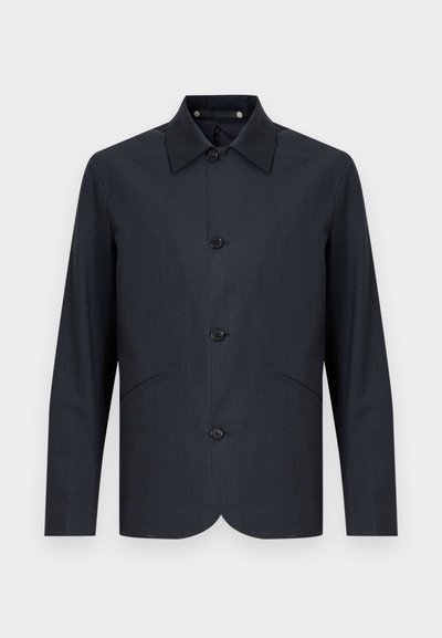 Sötét tengerészkék zakó sima anyagból, egyenes szabással, hegyes gallérral, hat gombbal és két első zsebbel.