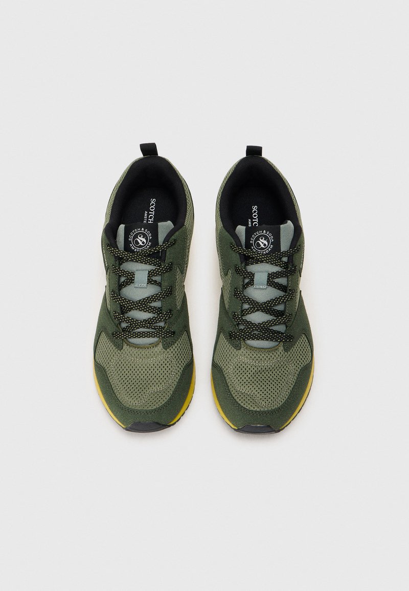 Gröna sportskor med mesh- och mockamaterial, rund tå, svarta snören och gul sula. Inkluderar branding på innersulan.