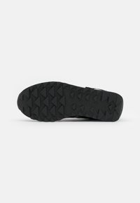 Zwarte sport- schoen zool, met een gestructureerde rubberen onderkant en driehoekige noppen voor grip. Glad afwerking met subtiele merkdetails.