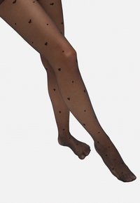 Pantys negras transparentes con un patrón de pequeños corazones negros en toda la superficie. Textura suave, forma ajustada y diseño de punta abierta.