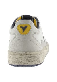 Sneaker bianco con texture, finitura in pelle screpolata, accenti gialli e grigi sul tallone e suola in gomma con motivo.