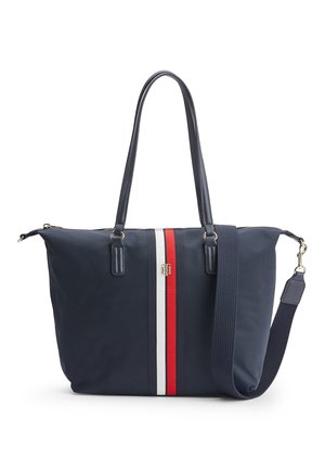 Granatowa torba na ramię z długimi uchwytami, czerwono-białe pionowe paski pośrodku oraz odpinany granatowy pasek na ramię.