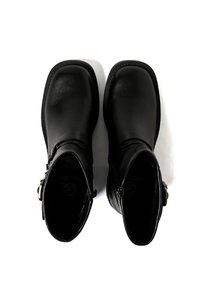 Stivaletti in pelle nera con una texture liscia, punta rotonda, cerniera laterale e dettagli decorativi a fibbia sul lato esterno.