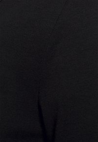 Tecido de malha ribbed preto, vista em close, com textura suave e ligeiro brilho, exibindo linhas diagonais e um design ajustado.