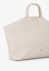 Borsa a tote in pelle beige con design strutturato, superficie testurizzata, manici corti e un accento triangolare alla base con il logo del marchio.