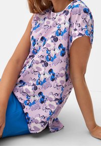 Blusa floreale viola con maniche corte, una texture morbida e un design astratto con accenti blu e rosa. Vestibilità leggera e fluida.
