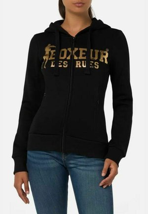 Felpa nera con zip realizzata in tessuto morbido, con un logo dorato "Boxeur des Rues" sulla parte anteriore, dotata di cordini e tasche frontali.