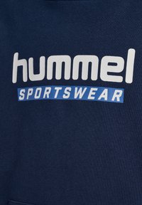 Felpa blu navy con una finitura strutturata che presenta un grande logo bianco "hummel" e un accento blu "SPORTSWEAR" posizionato sotto.
