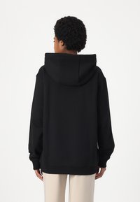 Black hooded sweatshirt with a relaxed fit, long sleeves, ribbed cuffs and hem, soft fabric texture, and minimalistic design.