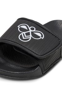 Black slide sandal with textured rubber strap and outsole. Features a contrasting white logo on the upper. Soft, flexible material.