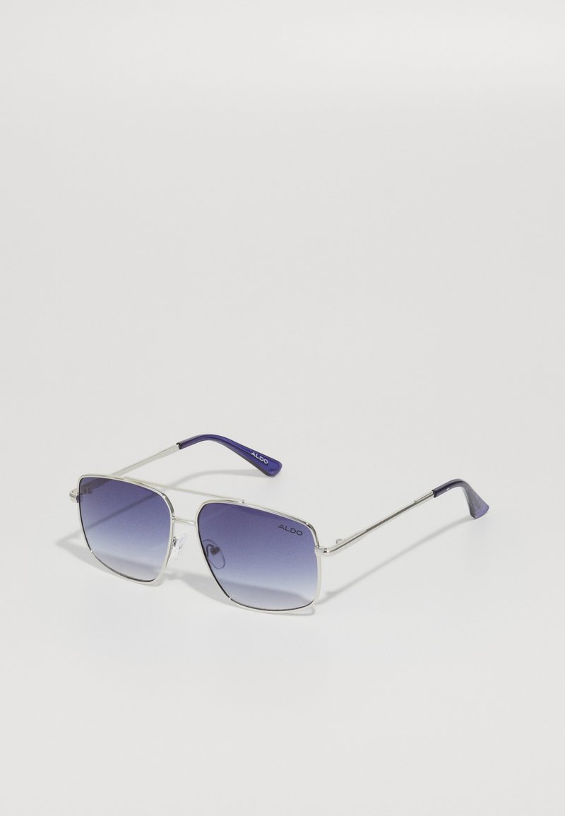 Lunettes de soleil carrées avec une monture en métal argenté et des verres dégradés violets. Elles présentent des embouts violets sur les branches et un design épuré et minimaliste.