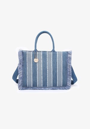 Sac cabas en tissu à rayures bleues avec des bords à franges, deux poignées et une étiquette métallique ronde attachée à une poignée.