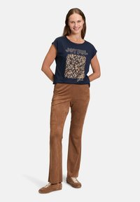 Navy short-sleeve top with "JOYFUL" text and leopard print in gold. Brown suede-like pants and brown sneakers complete the outfit.