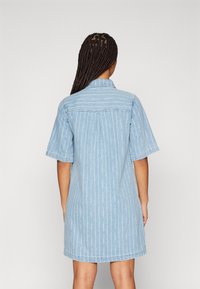 Lys blå denim skjortekjole med korte ermer, vertikale hvite striper, krage og rett snitt, som ender over kneet.