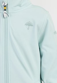 Felpa con zip di colore blu chiaro realizzata in morbido tessuto, con logo a ombrello ricamato sul petto e dettagli decorativi dei lacci.