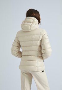 Beige Steppjacke mit horizontalen Steppnähten, einer enganliegenden Kapuze und Reißverschlusstaschen an den Seiten. Glatte, glänzende Stofftextur.