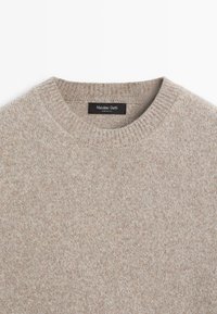 Maglione beige a maglia con colletto tondo. Texture morbida, orlo e polsini a costine. Etichetta con la scritta "Massimo Dutti, Made in Italy."