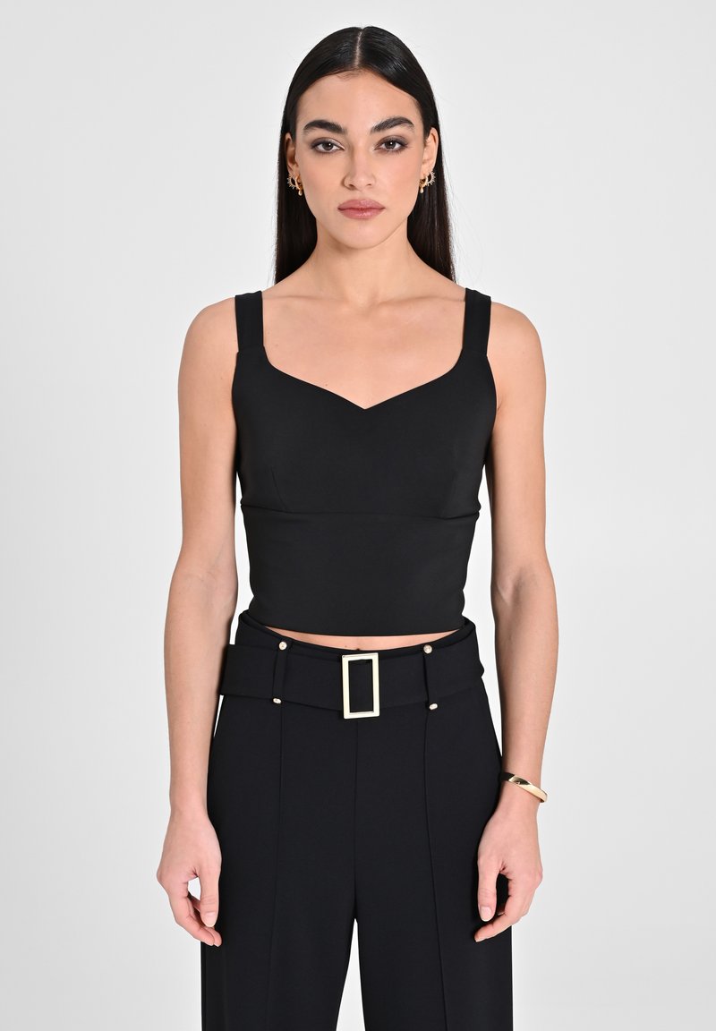 Top corto nero con spalline larghe, con un collo a forma di cuore. Abbinato a pantaloni neri su misura decorati con una fibbia rettangolare dorata.