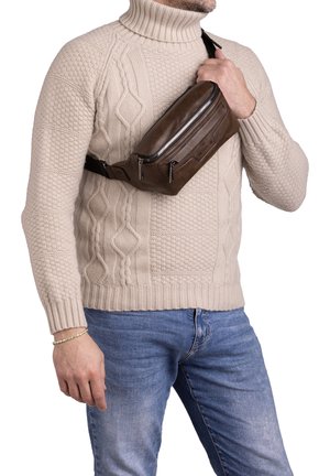 Sacca a tracolla in pelle marrone con una superficie liscia, dotata di due scomparti con zip e un design sottile e compatto, indossata a tracolla.