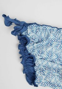 Bikini inferior de patrón azul con diseño de hojas, detalle de fruncido y un lazo atado en el costado, hecho de tela elástica.