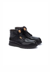 Bottes de randonnée en cuir noir avec une texture lisse, un design à lacets, un col rembourré et une semelle en caoutchouc. Présente un petit logo orange sur le côté.