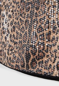 Leopardikuvioinen kangas, jossa mustia ja hopeisia paljetteja, teksturoitu pinta ja musta reunus, korostaen rohkeaa eläinkuviota.