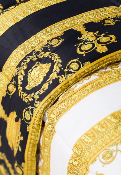Écharpe en soie avec un fond noir orné de motifs dorés complexes, incluant des motifs floraux et des bordures ornées, contrastée par des sections blanches.