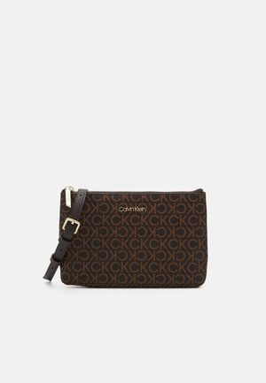 Brązowa kopertówka na nadgarstek Calvin Klein z powtarzającym się wzorem logo CK, regulowany czarny pasek ze skóry oraz złoty zamek błyskawiczny.