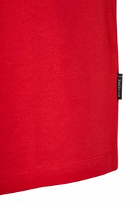 Rood katoenen t-shirt met een gestructureerd oppervlak; heeft een klein zwart label met witte tekst aan de zijnaad. Rechte zoom aan de onderkant.