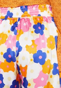 Tela de estampado floral multicolor con flores rosas, azules, naranjas y blancas. Presenta una cintura elástica y una textura suave.