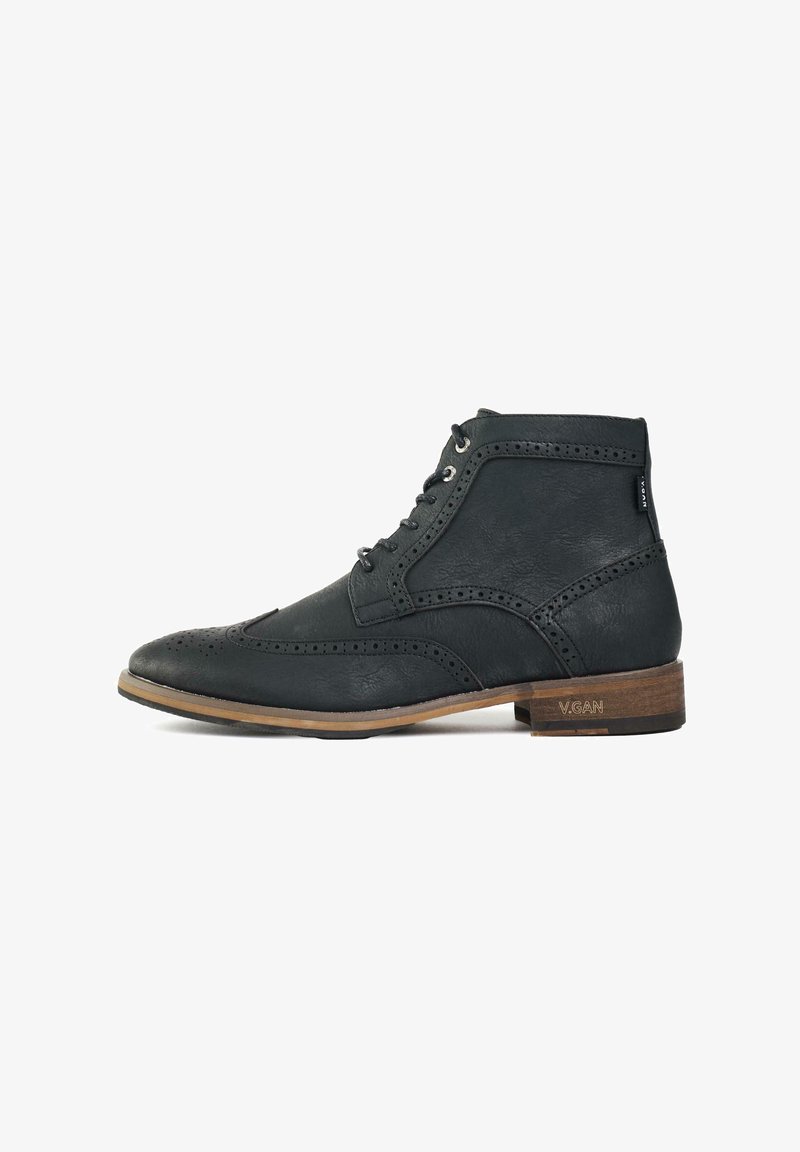 Black vegan leather ankle boot with brogue detailing, rounded toe, metal eyelets, and a tan wooden sole. Features logo on heel.