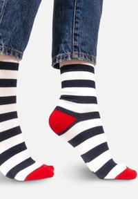 Skarpetki w paski w kolorze granatowym i białym, z poziomymi paskami, z czerwonymi akcentami w okolicy palców i pięty, wykonane z miękkiego, elastycznego materiału.