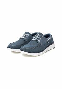 Zapatillas de lona azules con suelas de goma blanca, punta redondeada, diseño con cordones y detalles de costura en contraste.