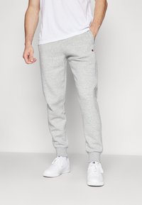 Grijze joggingbroek van zacht fleece materiaal, met een elastische tailleband, toelopende benen en een klein logo op de linkse heup.