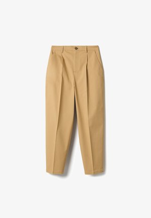 Broek in beige kleur, op maat gemaakt, met plooien aan de voorkant, zijzakken, ceintuurlussen en een knoopsluiting in de taille.