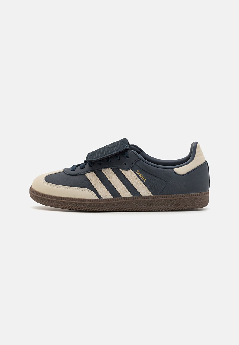 Marineblaue Ledersneaker mit cremefarbenen Akzenten, drei Streifen an der Seite, runde Zehenpartie und strukturiertem braunem Gummisohle. Klettverschlusslasche oben.