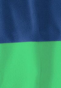 Μαλακό ύφασμα φλις με οριζόντιο σχέδιο, σκούρο μπλε πάνω και φωτεινό πράσινο κάτω, με ελαφριές πτυχώσεις και υφή.