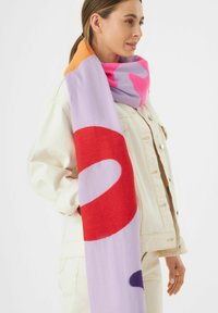 Écharpe colorée avec un m�élange de violet, orange, rose et rouge, ornée de formes abstraites audacieuses. Fabriquée en tissu doux, elle est drapée élégamment autour du cou.