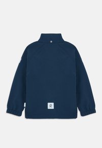 Granatowa kurtka z długim rękawem, z wysokim kołnierzem, elastycznymi mankietami i odblaskową naszywką logo na dolnej części pleców i rękawie.