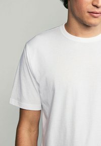 Witte katoenen t-shirt met korte mouwen, ronde hals en een gladde textuur, met een relaxte pasvorm en zonder zichtbare patronen of graphics.
